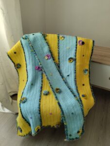 Couverture de laine jaune et bleue assortie à son écharpe